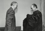 Chief Justice Edward D. Re of the U.S. Customs Court (right) assists Associate Justice Lewis F. Powell, Jr., into his regalia | 1980 Commencement