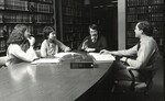 Professor Brook at table in faculty library, 4th floor of C building, with students